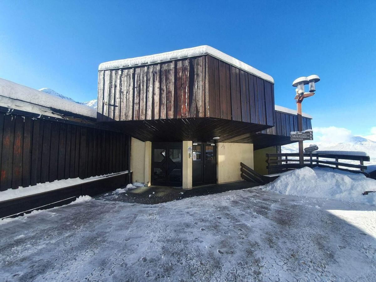 A wooden building with a covered entrance, a snow-covered ground, and a clear sky.
