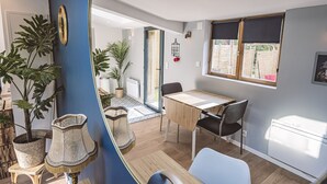Une cuisine moderne avec un coin repas, de grandes fenêtres et des plantes en pot.