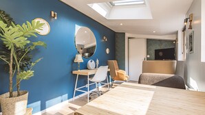 Une pièce moderne avec un mur d’accent bleu, une lucarne, une table en bois et une grande plante en pot.
