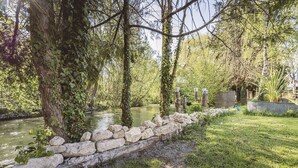 Un mur de pierre longeant une rivière, entouré de verdure et d’arbres.