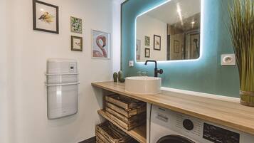 A compact bathroom with a sink, mirror, and a washing machine.