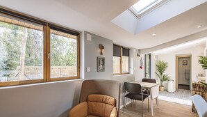 Un salon moderne doté d’une verrière, d’un coin repas et offrant une vue sur l’extérieur.