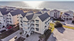 Uma área residencial costeira com edifícios de vários andares, um estacionamento e uma praia ao fundo.