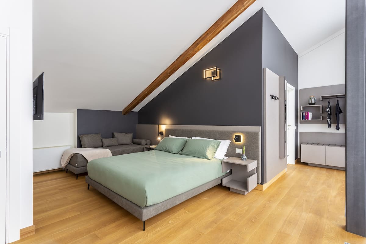 Een moderne slaapkamer met een bed in loftstijl, ingebouwde kasten en een houten balk.