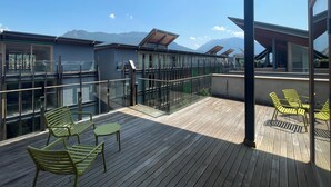 A wooden deck with outdoor seating, glass railings, and a mountain view. - Habitat Guest House (Trento)