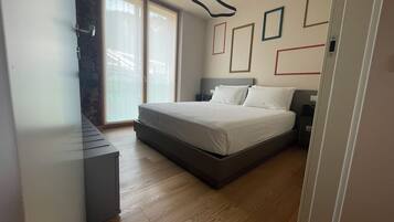Ein modernes Schlafzimmer mit einem großen Bett, einem Schreibtisch und einer Glastür, die auf einen Balkon führt.