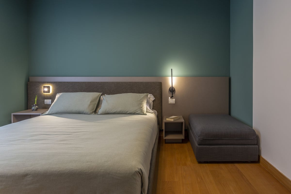 Een keurig opgemaakt slaapkamer met een bed, nachtkastjes en een bankje.