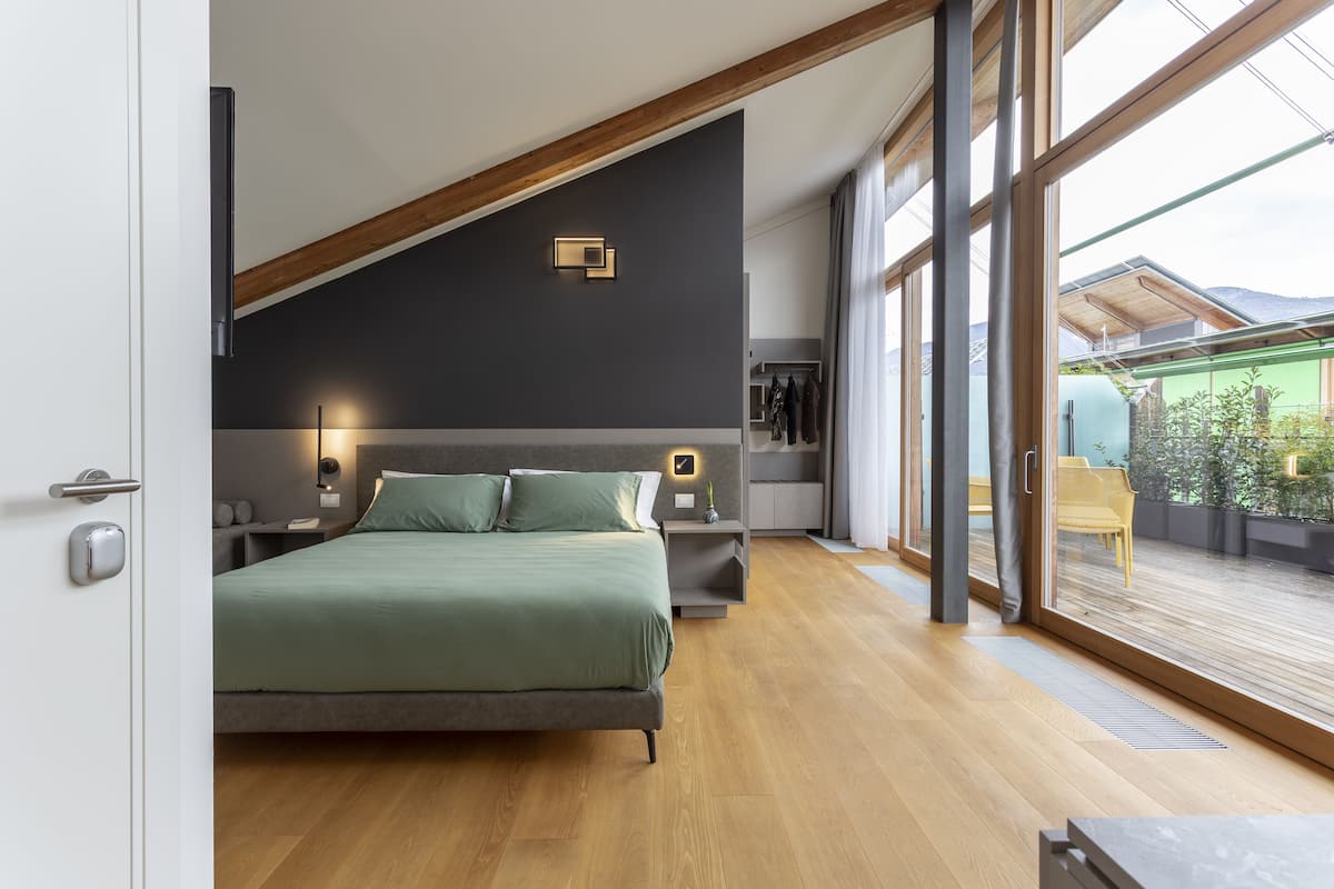 Een moderne slaapkamer met een groot bed, houten vloeren, een dakraam en uitzicht op de omgeving.