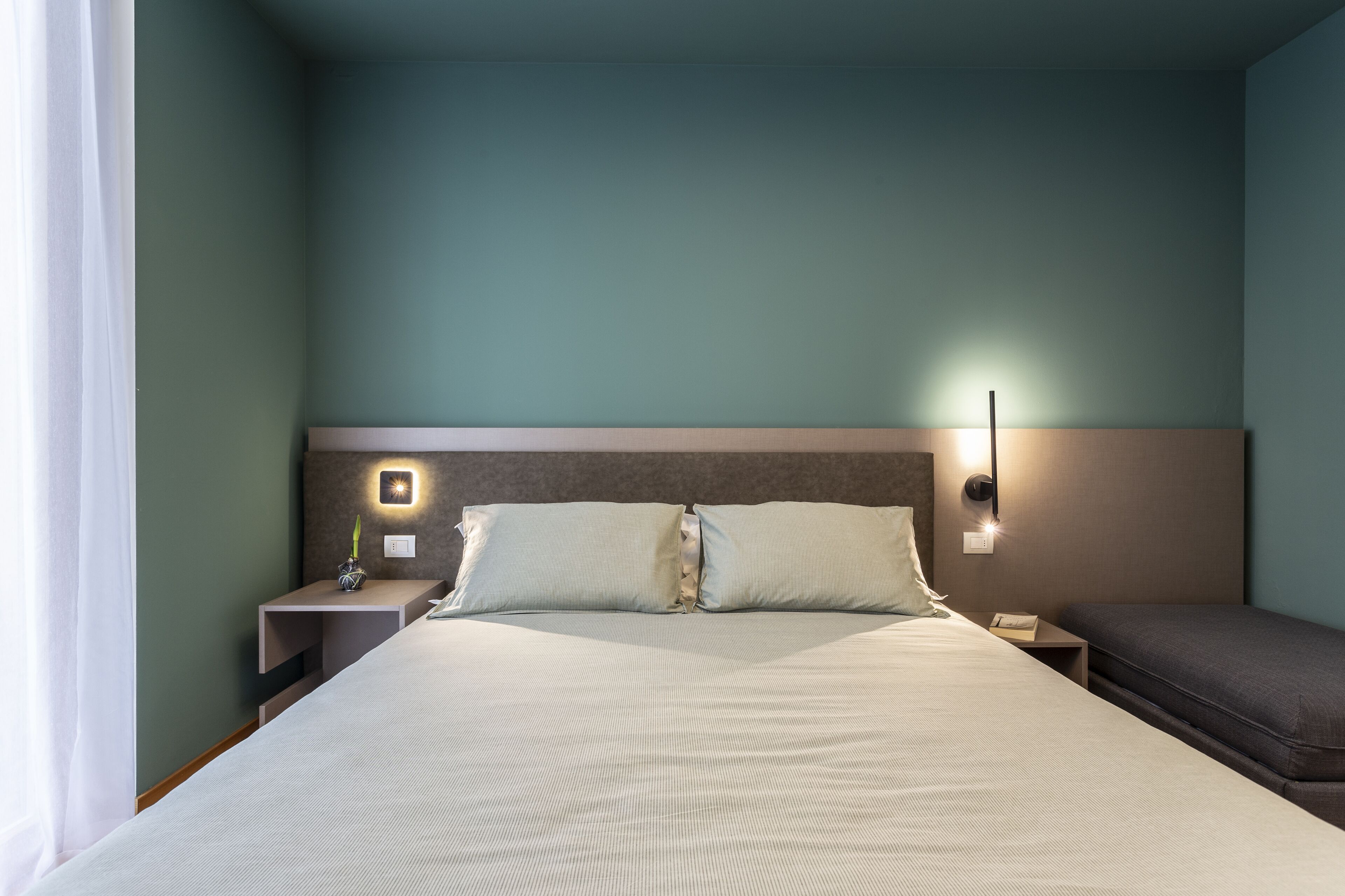 A hotel room with a large bed, a bedside table with a lamp, and a nightstand.