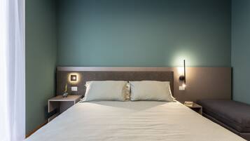 A hotel room with a large bed, a bedside table with a lamp, and a nightstand.