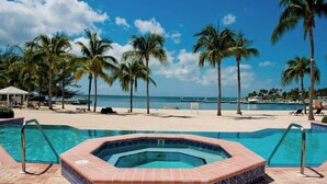 Ein Poolbereich mit Whirlpool, Palmen und Blick auf den Strand.