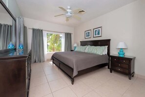 A bedroom with a bed, a ceiling fan, a dresser, and a nightstand.