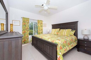 A bedroom with a bed, a nightstand, a dresser, a ceiling fan, and curtains. - Beachfront Crystal Kai 2BR -- Pool, Kayaks & Beach (Cayman Kai)