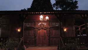 A traditional wooden building with a tiled roof and ornate carvings.