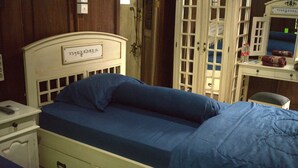 A single bed with a headboard, a nightstand, and a dresser with a mirror.
