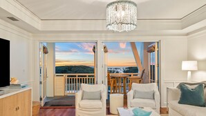 A spacious living room with a large TV, two white armchairs, a coffee table, and a balcony with a view of the landscape. - Gulf and Pool Views with Beach Access (Santa Rosa Beach)