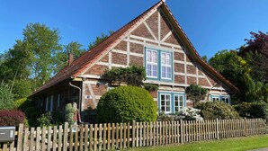A traditional half-timbered house with a wooden fence in front, surrounded by greenery. - Vacation home in the Elbtalaue to feel good all around (Dömitz OT Rüterberg)