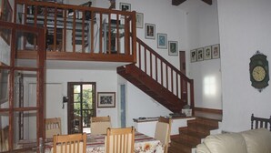 Ein Essbereich mit einer Holztreppe, einem Tisch mit Stühlen und einer Uhr an der Wand.
