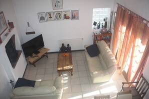 A living room with a sofa, a coffee table, a television, and a bookshelf.