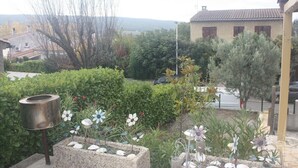 Ein Garten mit einem Steingartenbeet, einem Vogelhaus aus Metall und Zierblumen.