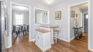Un coin repas avec une table et des chaises en bois, un buffet blanc et un miroir au mur.