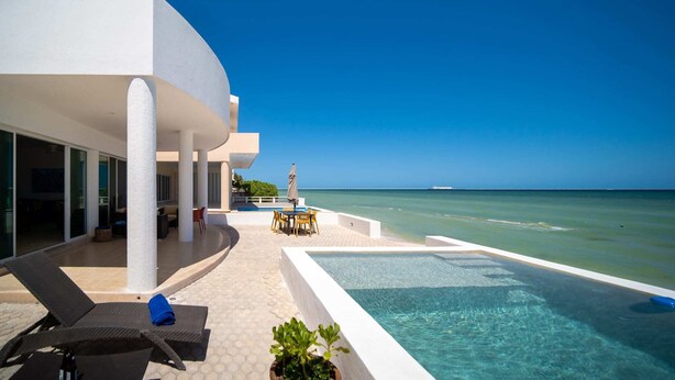 Ein modernes Resort mit Pool, Liegestühlen und Blick aufs Meer.
