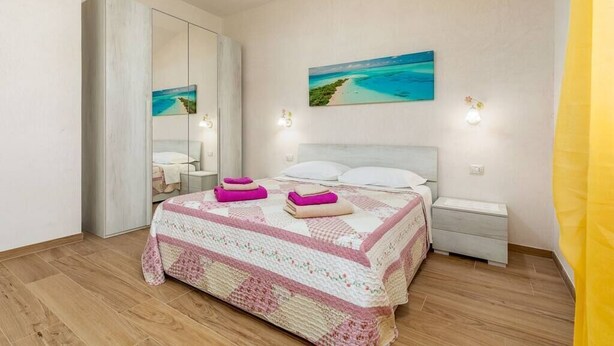 Une chambre à coucher avec un lit, des tables de chevet, une commode, un miroir et un tableau au mur.