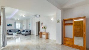 Un vaste espace de vie comprenant un canapé, une armoire en bois et une petite table sur laquelle est posé un vase.