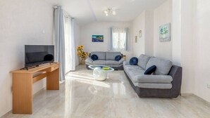 Un salon moderne avec un téléviseur, un canapé et une table basse.