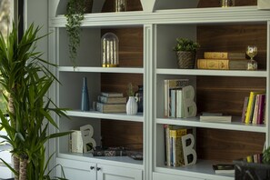 A bookshelf with books, decorative items, and a plant. - Balèze Boutique Hotel - Adults Only (Ula)