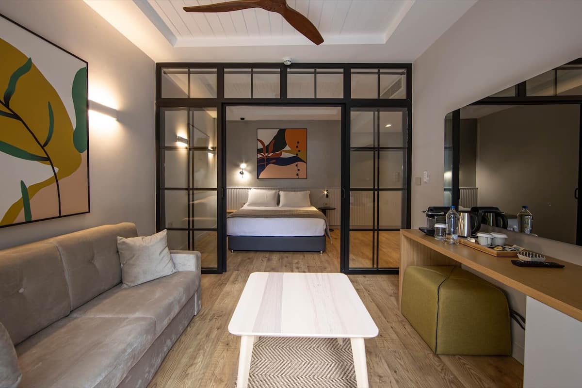 A modern bedroom with a bed, a sofa, a dining area, and a kitchen.