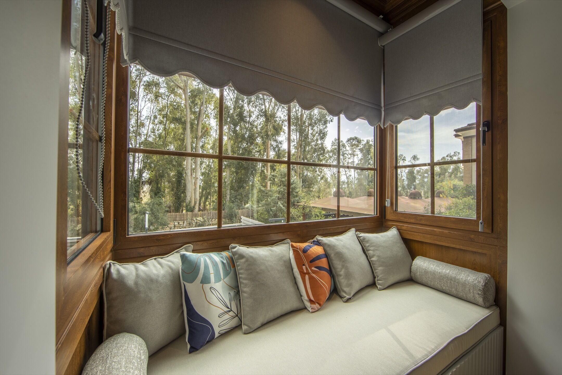 A room with a built-in bench along a large window with a view of trees.