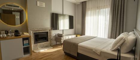 A modern hotel room with a fireplace, a bed, a desk, and a large mirror.