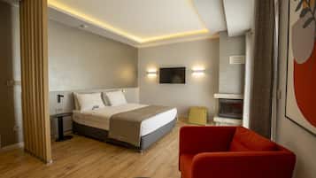 Una habitación de hotel moderna con una cama, una silla roja, una mesita pequeña y un televisor de pantalla plana montado en la pared.