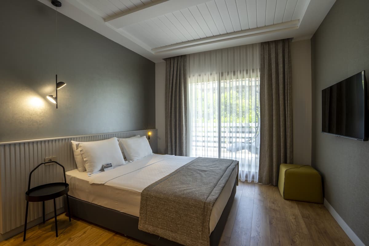 A modern bedroom with a bed, bedside table, and a TV mounted on the wall.
