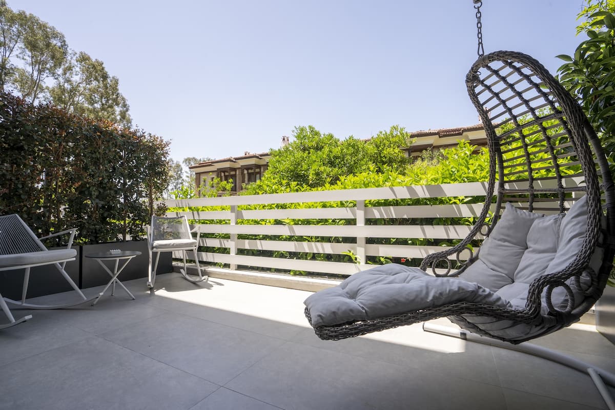 A patio with a hanging chair, a table, and a chair.