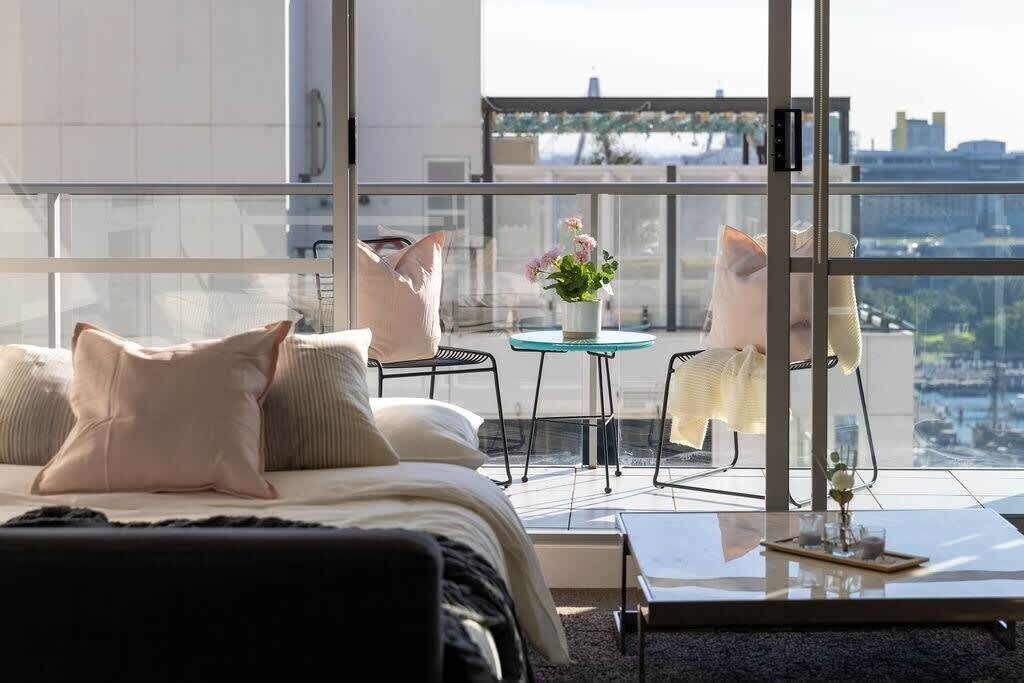 A modern bedroom with a large bed, a glass table, and two chairs.