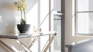 Un interior moderno con una mesa de mármol, una planta en maceta y vistas al exterior a través de amplios ventanales.