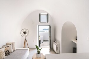 A modern, minimalist room with a sofa, a floor lamp, and a potted plant.
