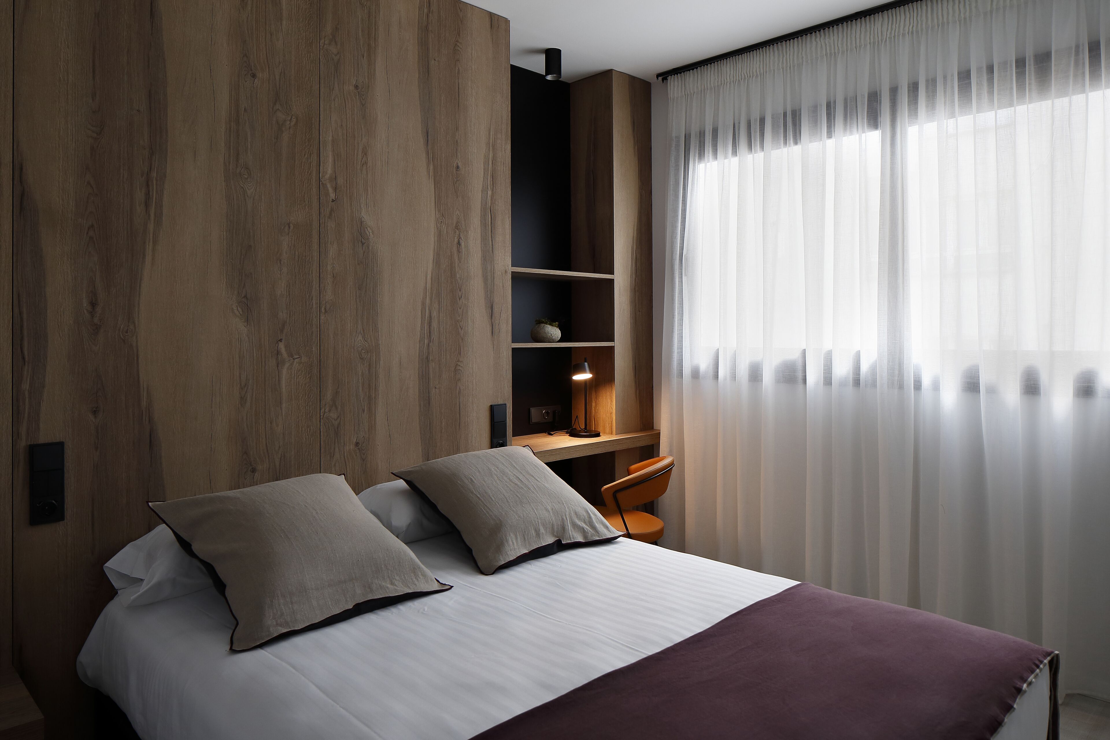 Une chambre à coucher moderne avec un grand lit, un bureau et une chaise.