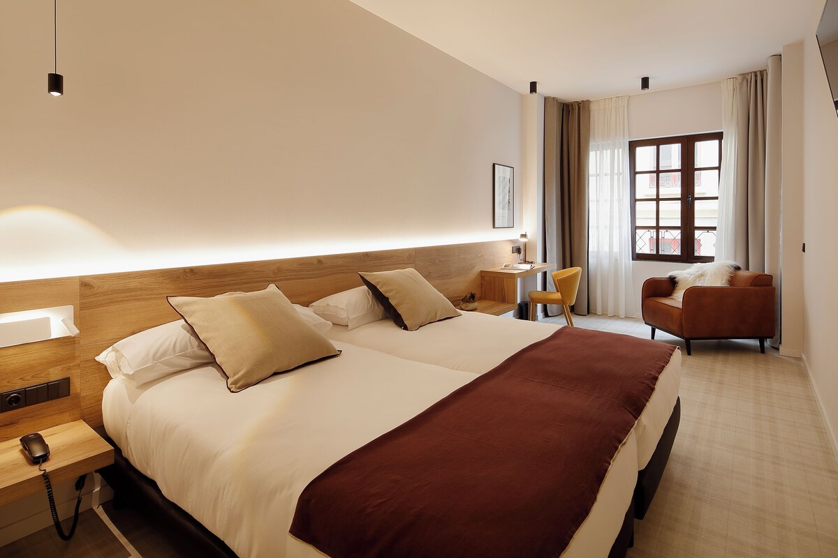 Een hotelkamer met een groot bed, een bureau, een stoel en een raam met gordijnen.