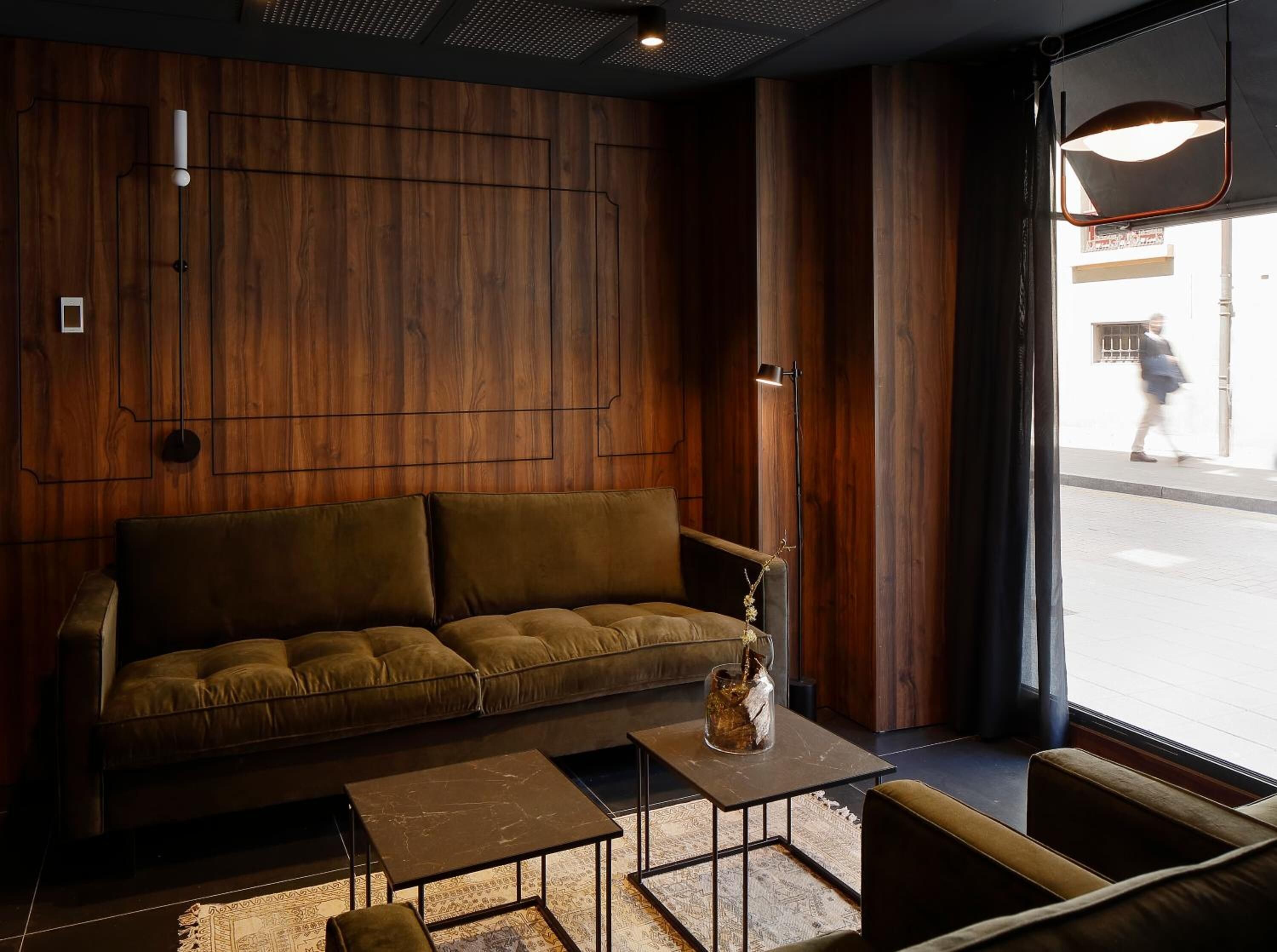 A modern interior with a wooden wall, a brown sofa, a small table, and a vase.