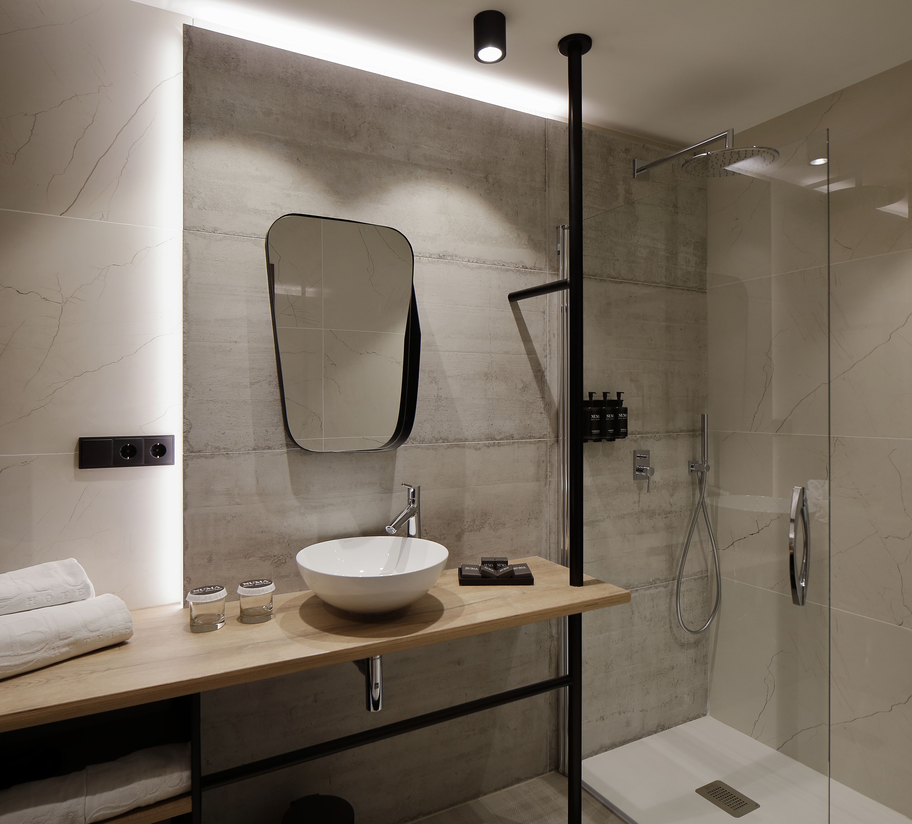 A modern bathroom with a large mirror, a sink, and a shower.