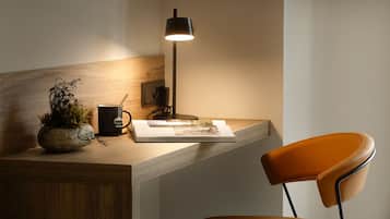 Un espacio de trabajo con un escritorio de madera, una lámpara, una taza, un libro y una silla.