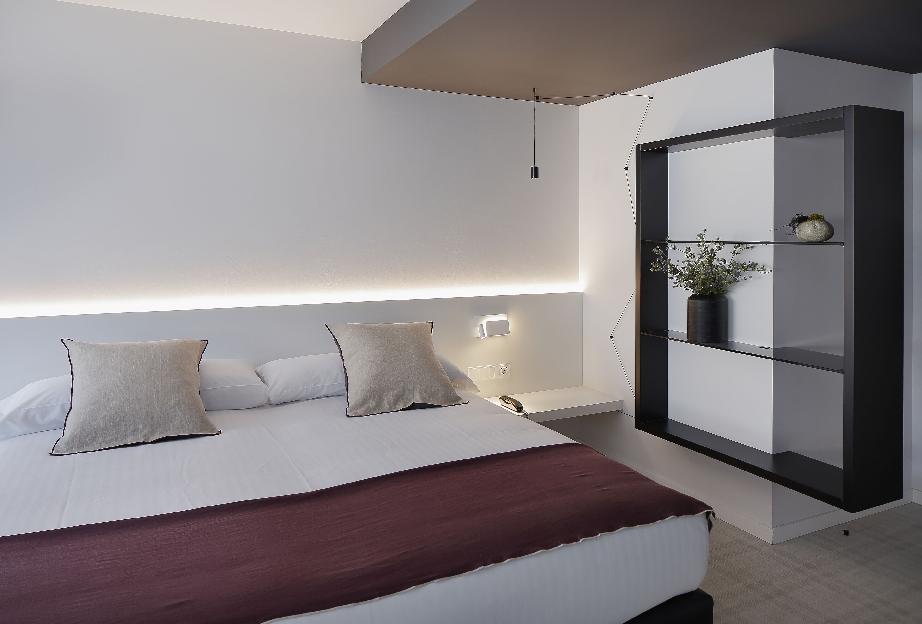 Un dormitorio moderno con una cama grande, mesitas de noche, un armario empotrado y una lámpara colgante.