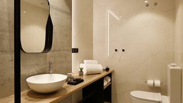 Un baño moderno con un espejo grande, un lavabo, un inodoro y una zona de ducha.