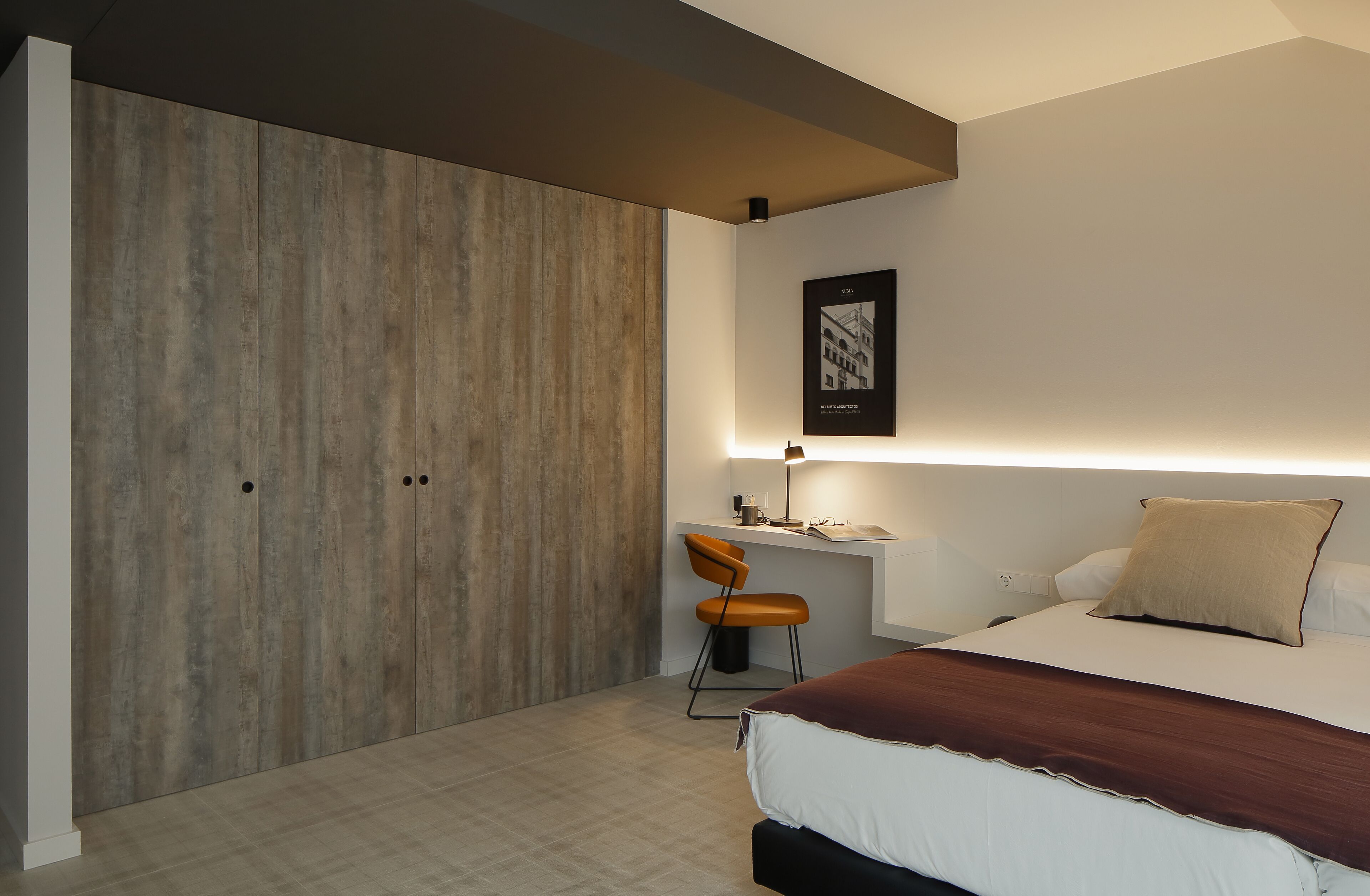 A modern bedroom with a bed, a desk, and a chair.