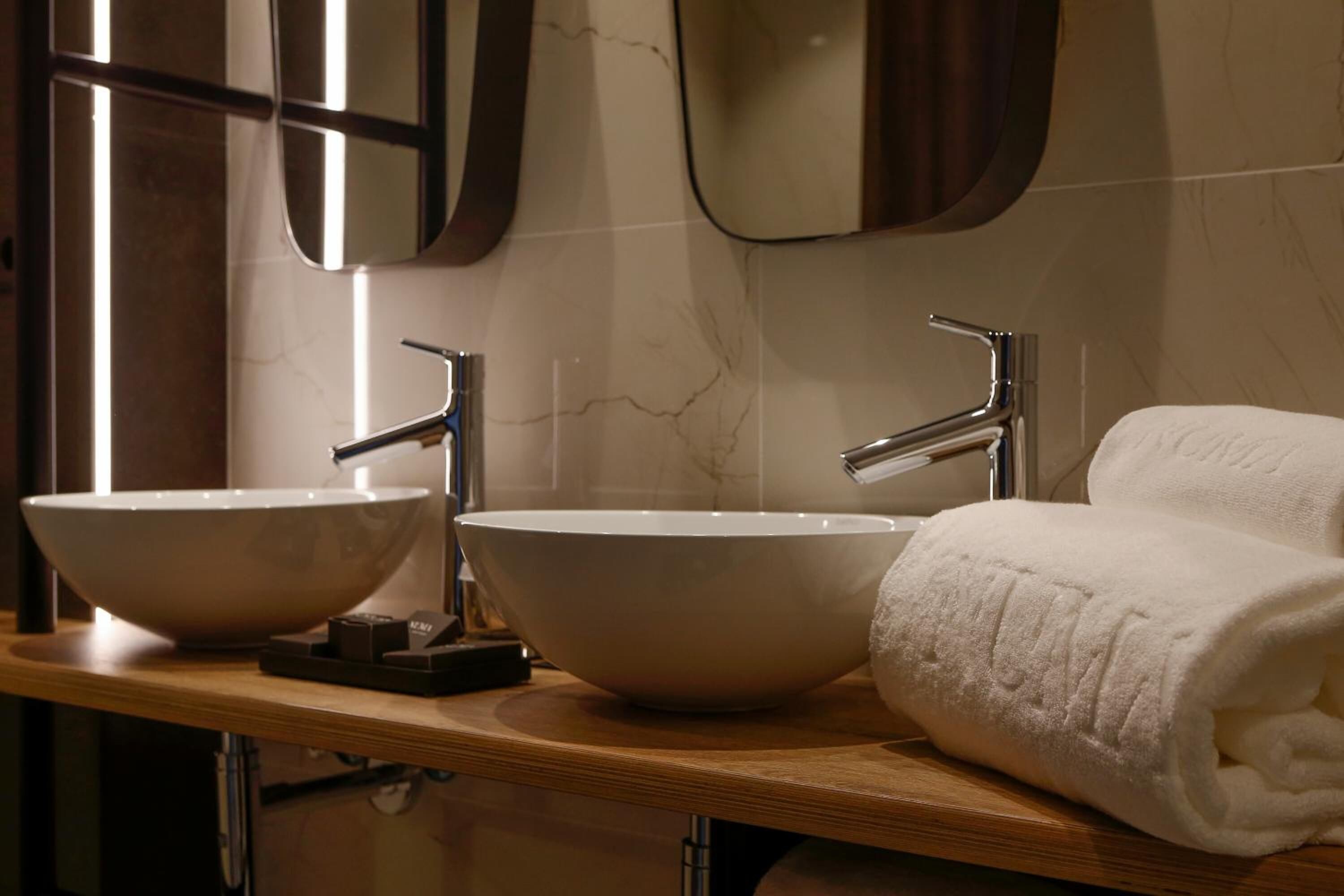 A bathroom with two large white bowls as sinks, a towel, and a mirror.
