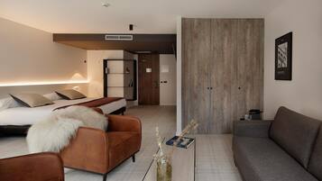 Habitació d'hotel moderna amb llit, sofà, taula de cafè i un ampli panell de paret de fusta.