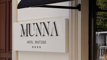 Segnaletica per "MUNNA HOTEL BOUTIQUE" con un tendone nero sopra.